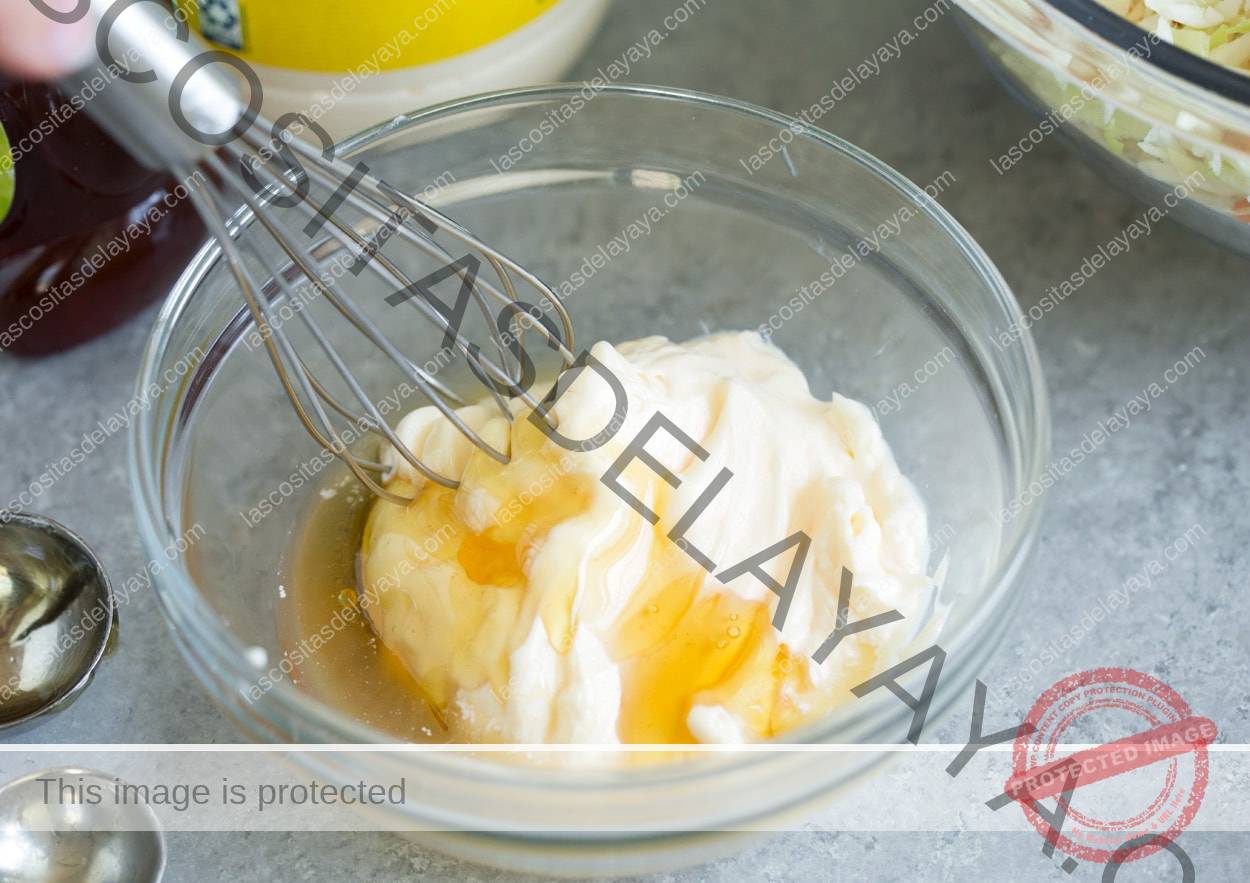 Prepara el aderezo de ensalada de col en un bol con 3 ingredientes, entre ellos mayonesa, miel y vinagre de manzana.
