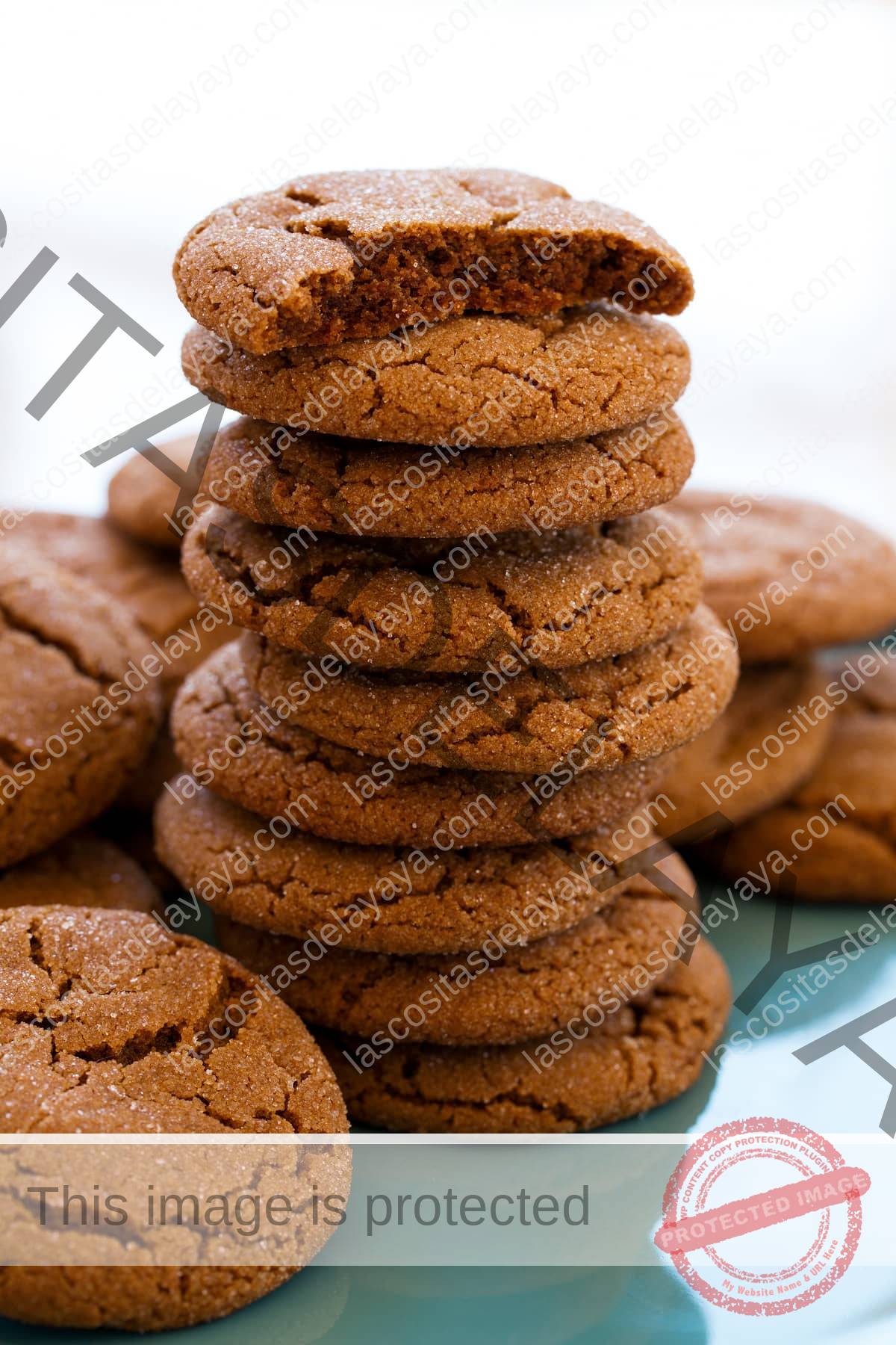 Montón alto de galletas de melaza con la galleta superior partida por la mitad para mostrar la textura suave y húmeda del interior.