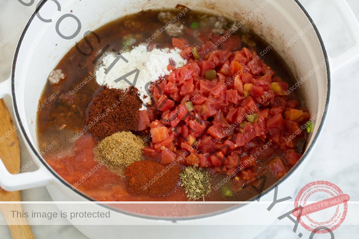 Agregue tomates y especias a la sartén para hacer una sopa de tacos.