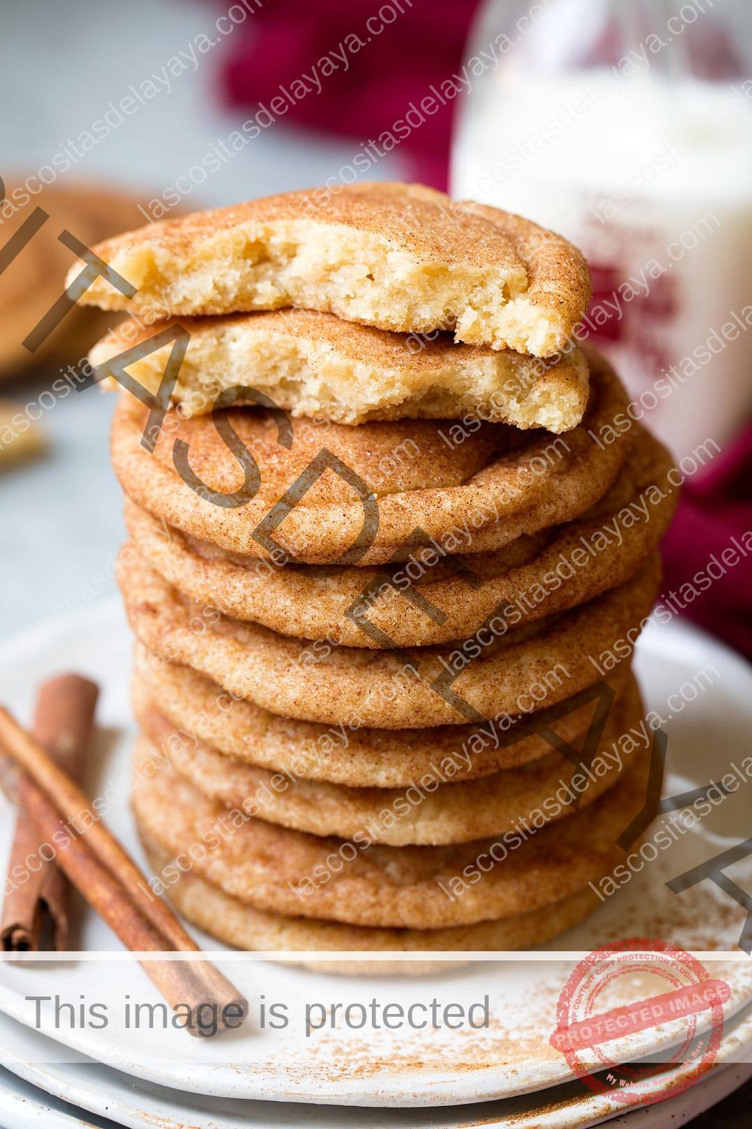 Pila de galletas snickerdoodle en un plato con un cooke en la parte superior partido por la mitad para mostrar la textura del interior.