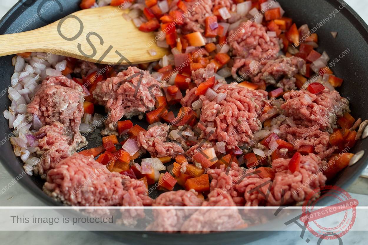 Dorar carne picada y cebollas en una sartén para hacer carne de res y arroz chimichurri